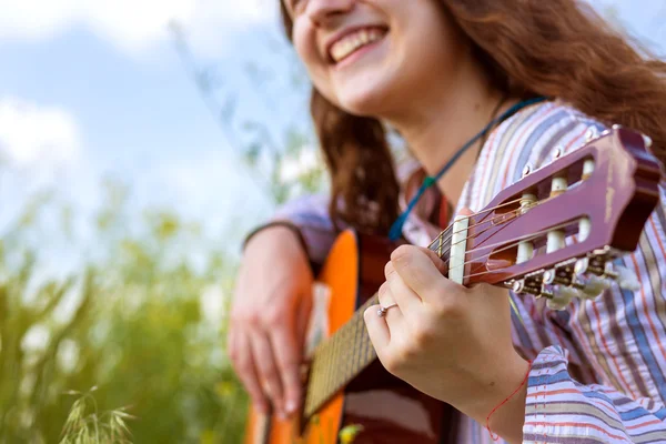 Vrouwelijke muzikant zittend op groene gras zijaanzicht — Stockfoto