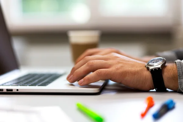 Man werkt op een laptop in een gezellige omgeving met koffie — Stockfoto