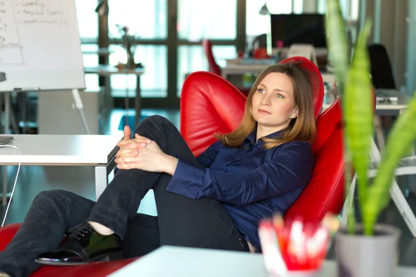 İş modern yaratıcı ofisinde kırmızı sandalyede oturan Bayan — Stok fotoğraf