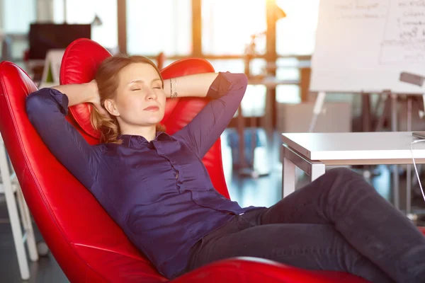 Unternehmerin entspannt im roten Stuhl im modernen Büro — Stockfoto