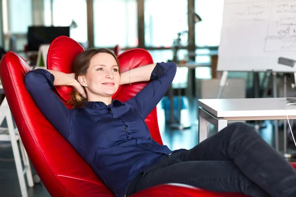 Persona de negocios relajante en silla roja en la oficina creativa moderna — Foto de Stock