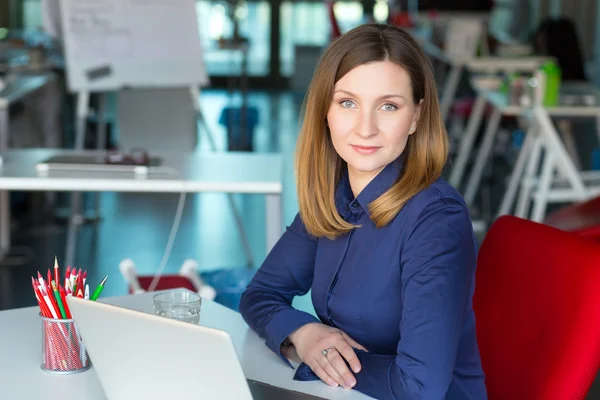 Smiling Business Lady in casual clothing sitting at Office Table