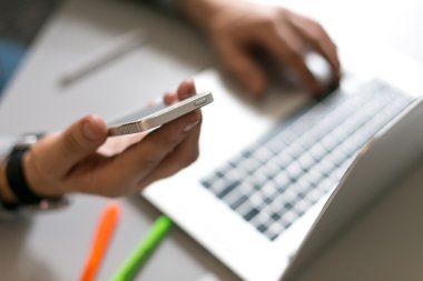 Telefon tutarak ve dizüstü bilgisayarda çalışan adam