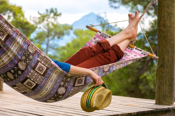 Person relaxing in Hummock holding Travel Hat — Stock Photo, Image
