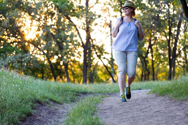 Mujer despreocupada caminando por el sendero forestal al atardecer — Foto de Stock