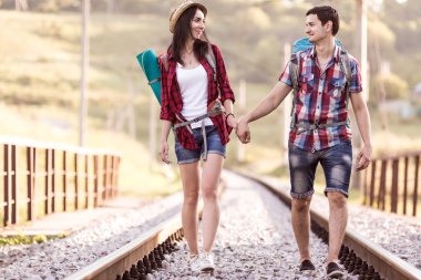 Two Hikers walking along Railroad holding Hands clipart