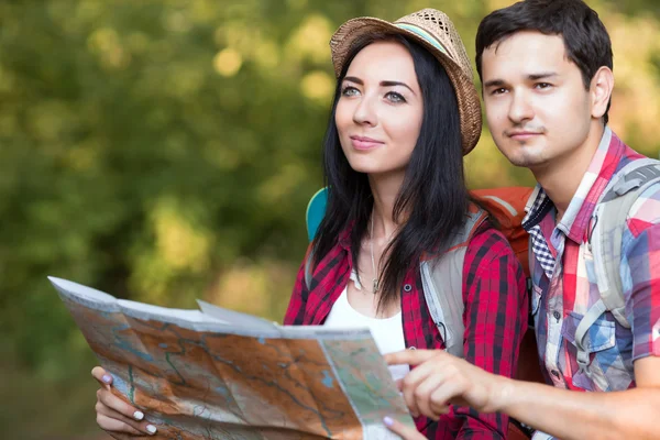Jonge vrouw en Man met rugzakken reis kleding houden kaart — Stockfoto