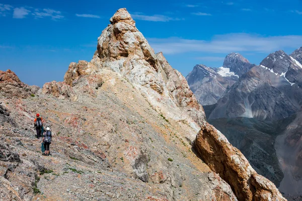 かみそり鋭い岩山頂と登山者のグループに接近 — ストック写真