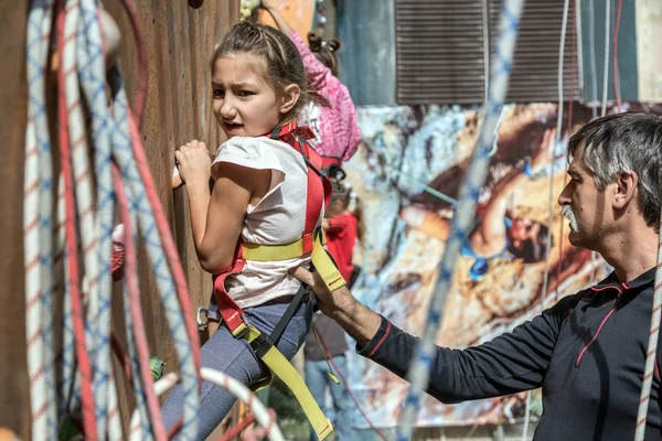 Liten flicka klättrar vägg farfar bistå henne — Stockfoto