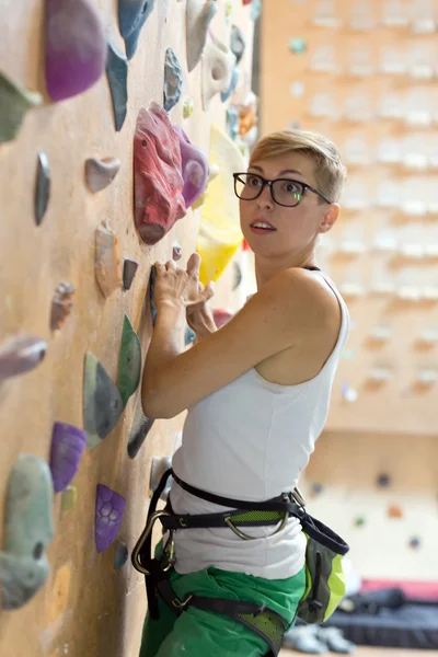 Joven escaladora femenina en la pared del gimnasio de escalada interior —  Fotos de Stock