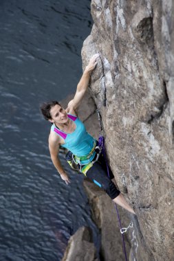 Female rock climber hanging over the abyss clipart
