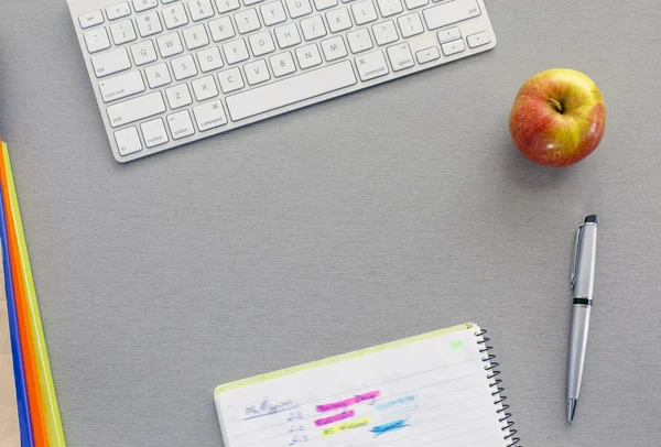 Espacio de trabajo de oficina en escritorio gris con manzana roja —  Fotos de Stock