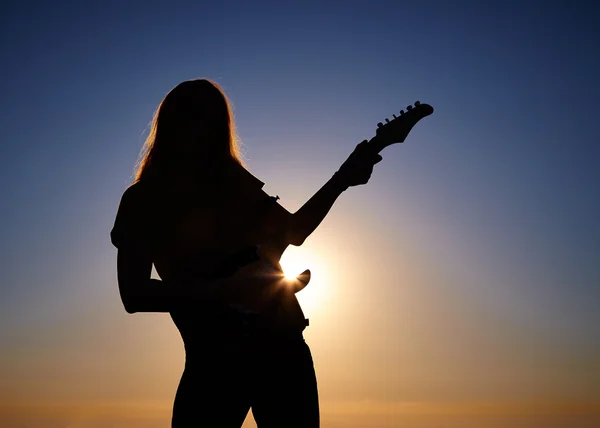 Silhouette of female busker in front of sunrise — Stock Photo, Image