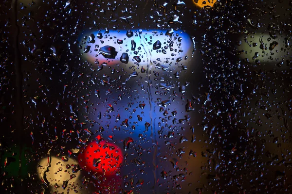 Raindrops on the window with urban night lights — Stock Photo, Image