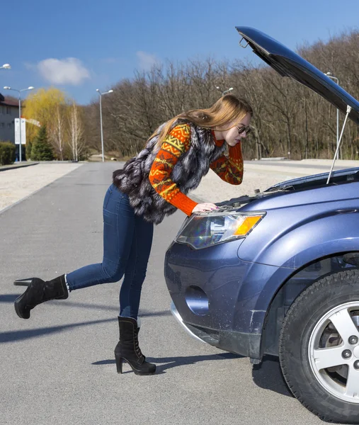 Vrouwelijke bestuurder inspecteert haar auto-motor — Stockfoto