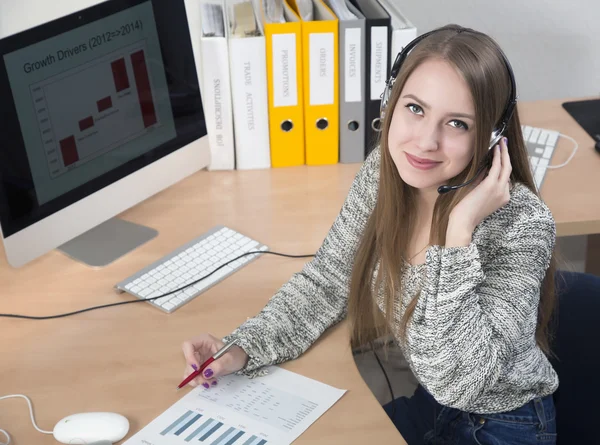 Jonge zakenvrouw met hoofdtelefoon op in de office-interieur — Stockfoto