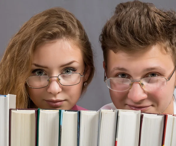 Young guy and girl above stack of books — Stock Photo, Image