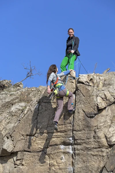 Bergsteigerin hilft ihrem Partner, den Gipfel zu erreichen — Stockfoto