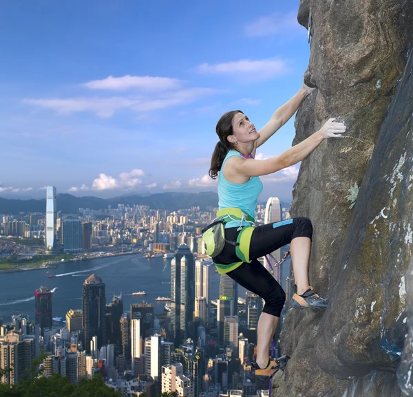 Kvinnliga rock klättrare över stadens silhuett — Stockfoto