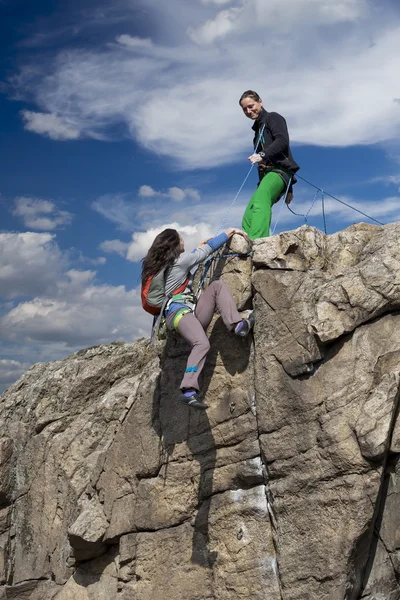 Bergsteigerin hilft ihrem Partner, den Gipfel zu erreichen — Stockfoto