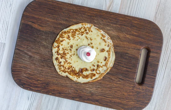 Gebakken ronde pannenkoek met room en berry op donkere hout achtergrond — Stockfoto