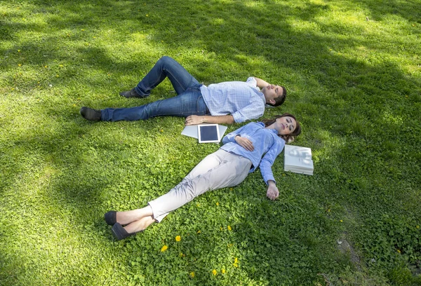 Ung man och kvinna tupplur på gräsbevuxen gräsmatta — Stockfoto