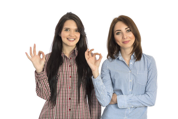 Two cheerful girls makes OK hand sign