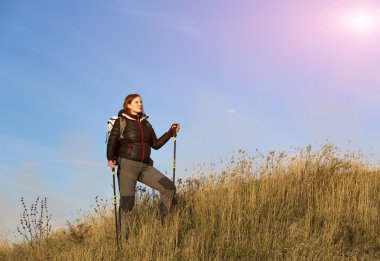 Female hiker walking on grassy hill