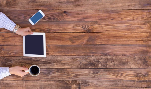 From above image of man browsing gadget at empty wood desk