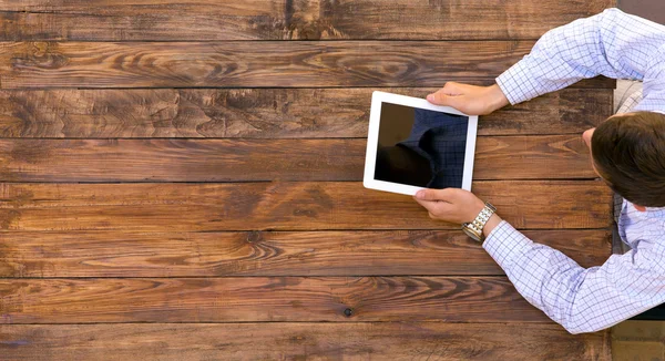 Man holding tablet PC sitting at vintage handcrafted wooden desk — Stock Photo, Image