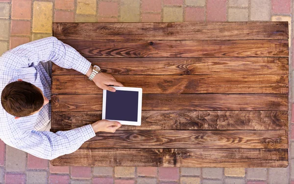 Homme tenant tablette PC assis au bureau en bois artisanal vintage — Photo