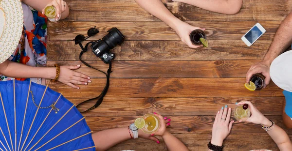Skupina uvolněný lidí pití koktejlů na dřevěný stůl — Stock fotografie