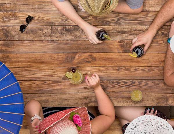 Group of relaxed people drinking cocktails at wooden table — Stock Photo, Image