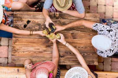 Summer vacation style dressed group young people relaxing with cocktails at cafe terrace bar vintage rough wooden desk directly from above clipart