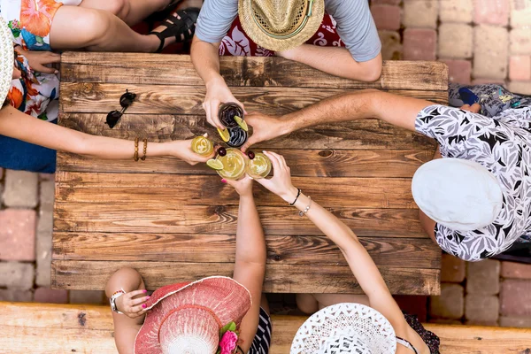 Летний отдых стиль одетой группы молодых людей расслабляющий с коктейлями в кафе терраса бар винтажный грубый деревянный стол прямо сверху Стоковое Фото