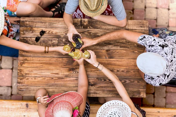 Summer vacation style dressed group young people relaxing with cocktails at cafe terrace bar vintage rough wooden desk directly from above — Stock Image Summer vacation style dressed group young people relaxing with cocktails at cafe terrace bar vintage rough wooden desk directly from above Royalty Free Stock Images