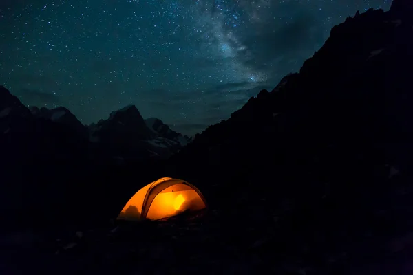 Нічний гірський пейзаж з освітленим наметом — стокове фото