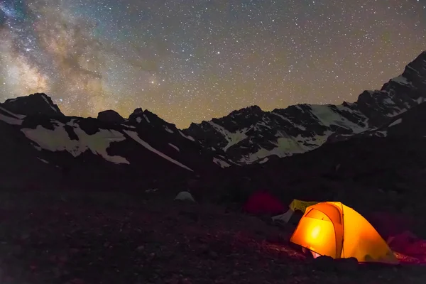Night mountain landscape with illuminated tent