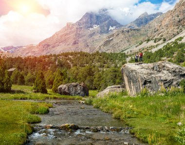 Mountain Stream and Female Hikers on Rock