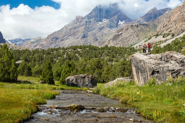 Corriente de montaña y excursionistas femeninas en el rock — Foto de Stock