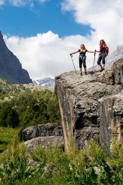 Two hikers staying on rock