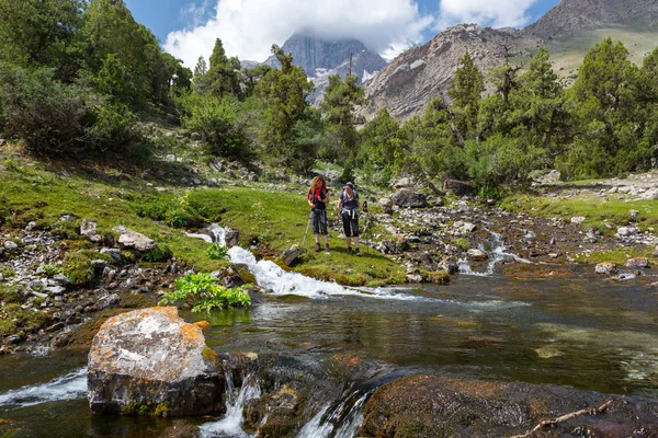 Hikers staying on shore of mountain rive — Stock Photo, Image