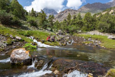 People relaxing next to mountain river