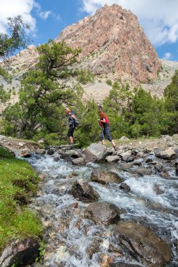 Two hikers crossing fast flowing river