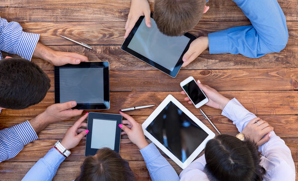 Мужчины и женщины пристально смотрят на экраны цифровых гаджетов
