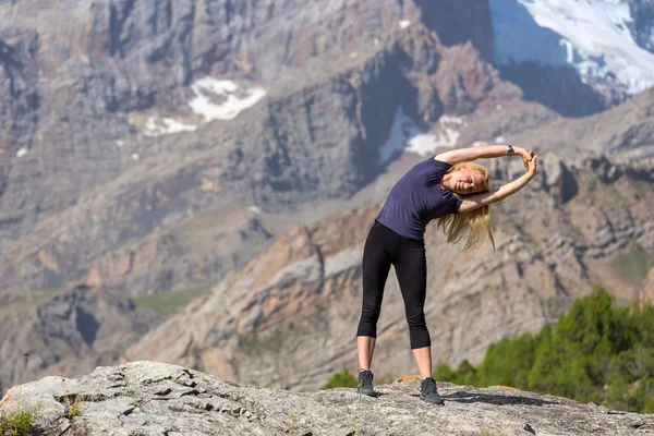 Mujer joven haciendo gimnasia matutina al aire libre en el paisaje de montaña —  Fotos de Stock