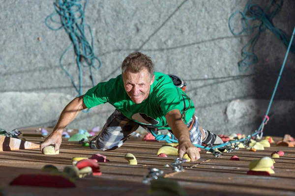 Usmívající se starší muž na extrémní lezecké stěně — Stock fotografie