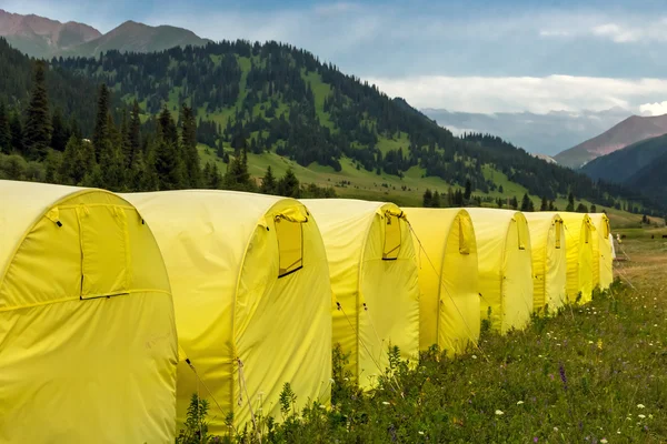 Línea de muchas tiendas de campaña amarillas en el paisaje de montaña — Foto de Stock