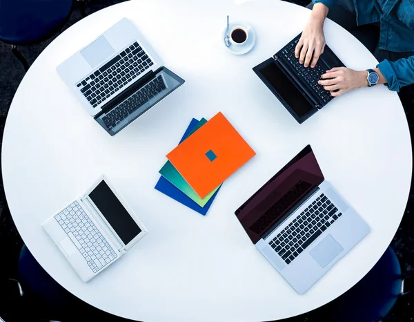 Top View of Rounded Desk with Four Laptops and Male Hands Typing on Keyboard — Stock Fotó