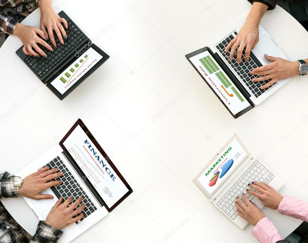 Top View of Rounded Desk with Four Laptops and People Hands Typing on Keyboard